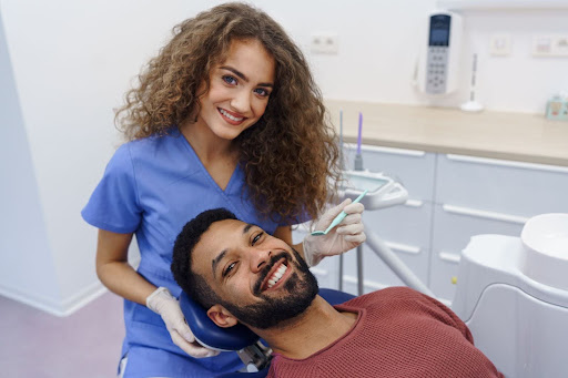 The female dentist smiles after examining a multiracial mans teeth for possible filling needs.