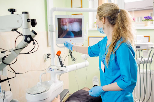 A female dentist analyzes the live intraoral picture of the patients teeth.
